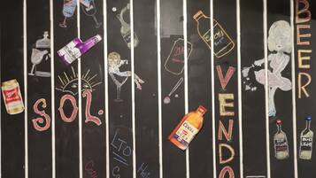 Una pizarra con líneas verticales blancas, decorada con diversas ilustraciones de botellas de cerveza y texto.