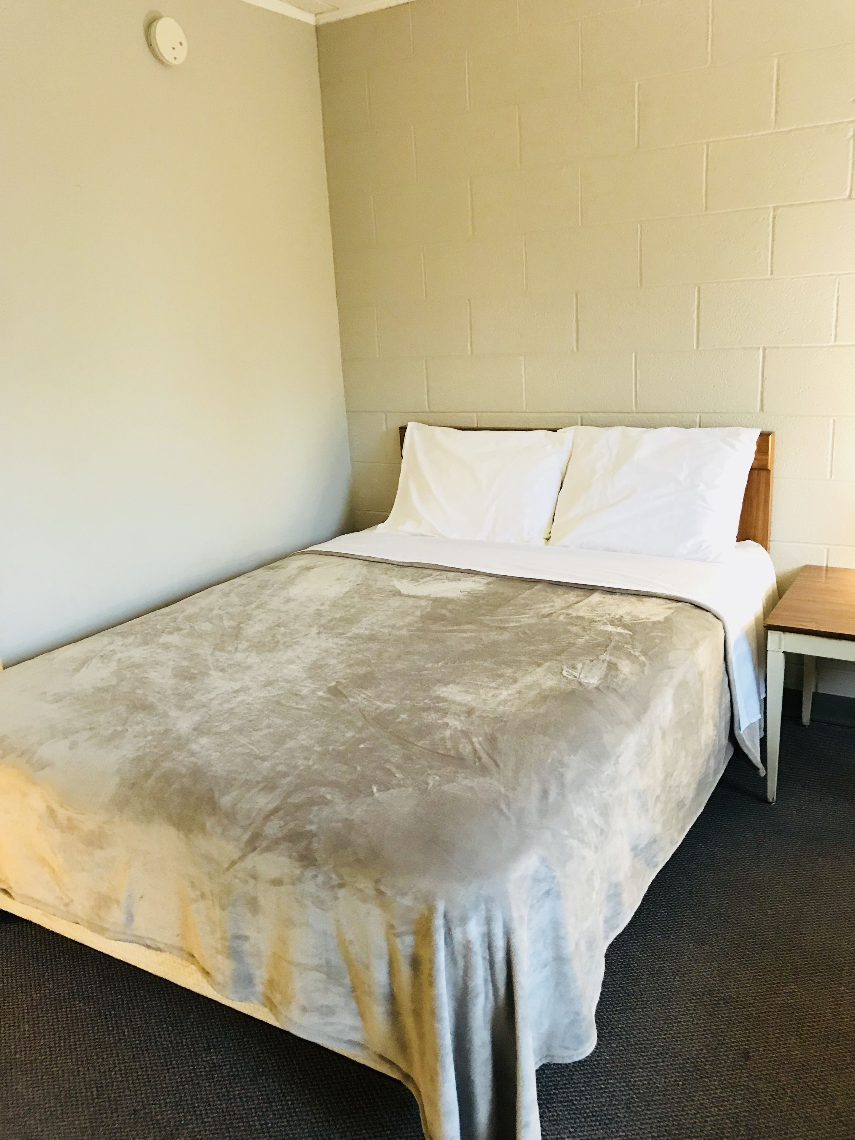 A hotel room with a bed, a small table, and a brick-patterned wall.