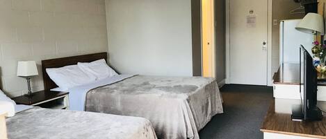 Habitación de hotel con dos camas, un escritorio con computadora, televisión y lámpara.