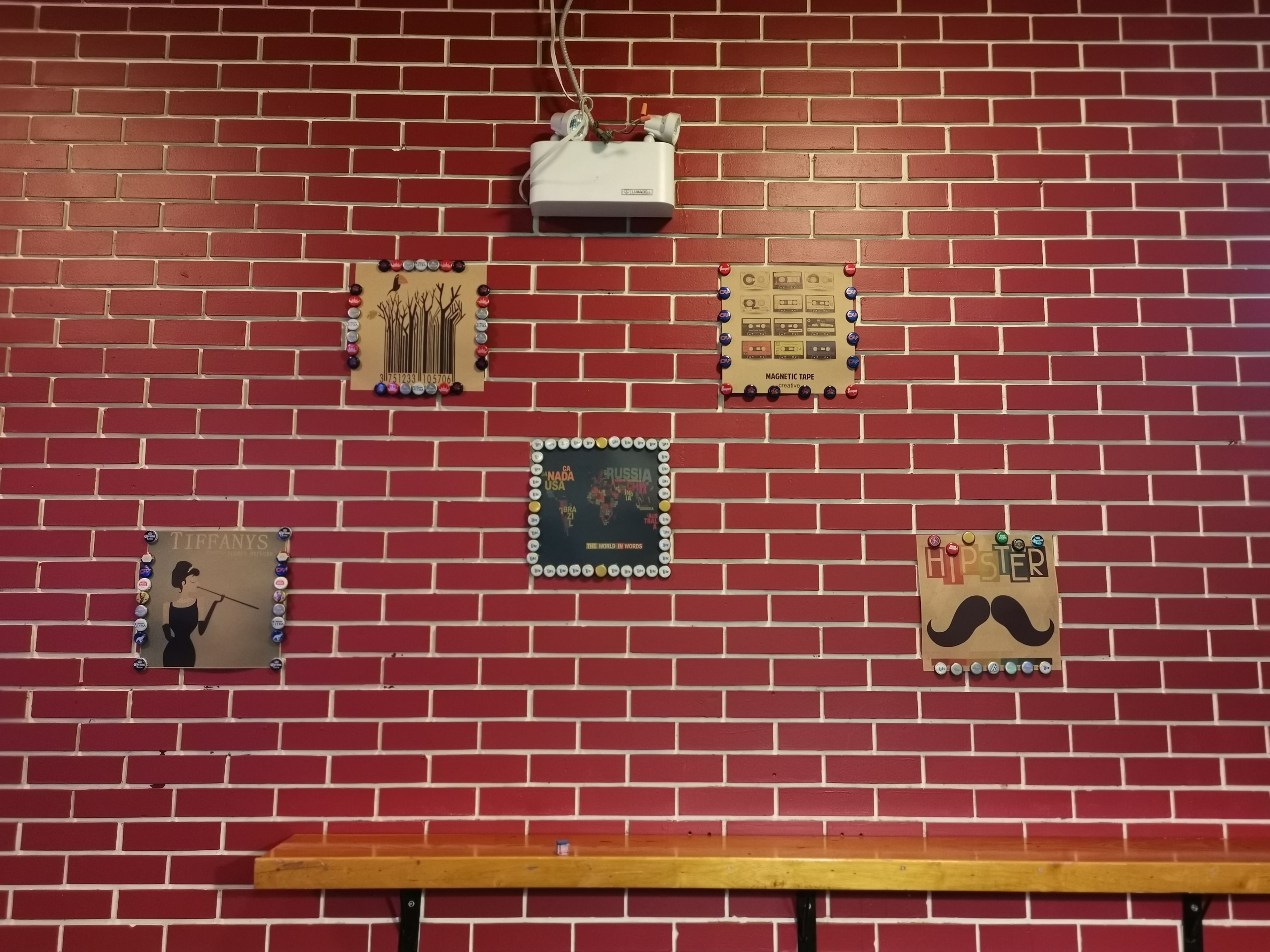 A red brick wall with various decorative items, including a framed picture of a woman, a map, and a magnetic tape display.