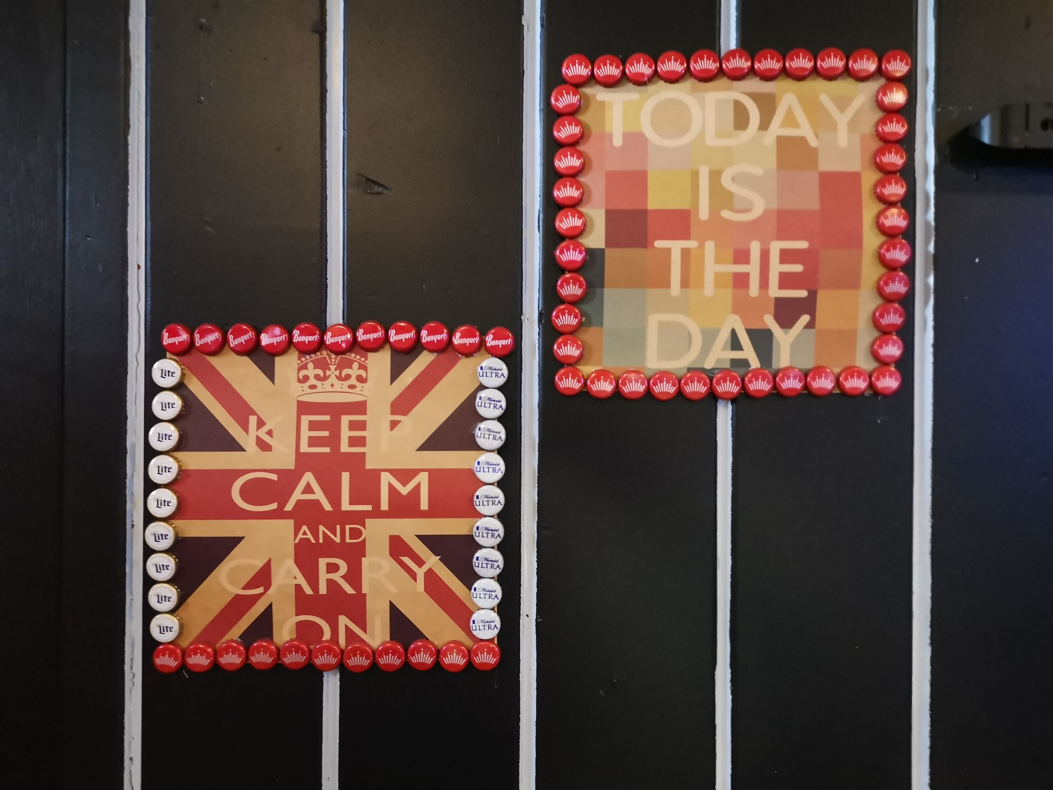 Two signs on a wall with a pattern of red and white buttons. One sign says "KEEP CALM AND HARNESS" and the other says "TODAY IS THE DAY".