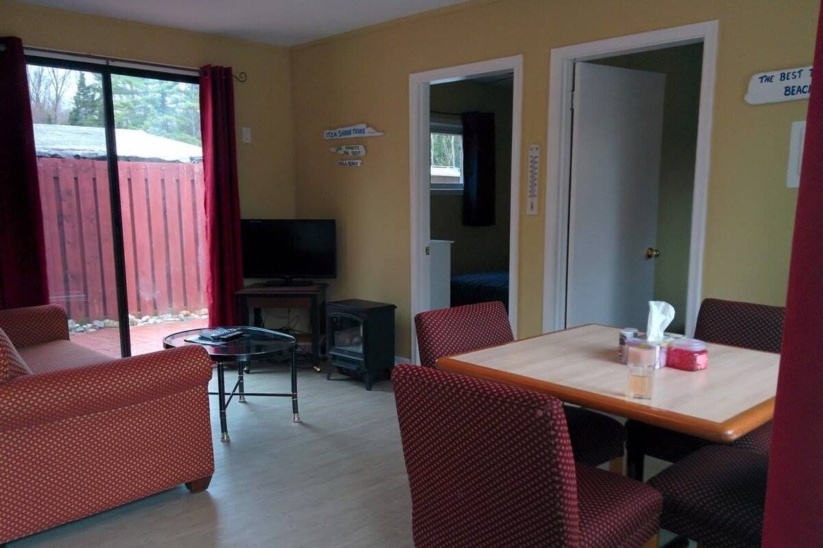 A room with a dining table, red upholstered chairs, a television, and a fireplace.