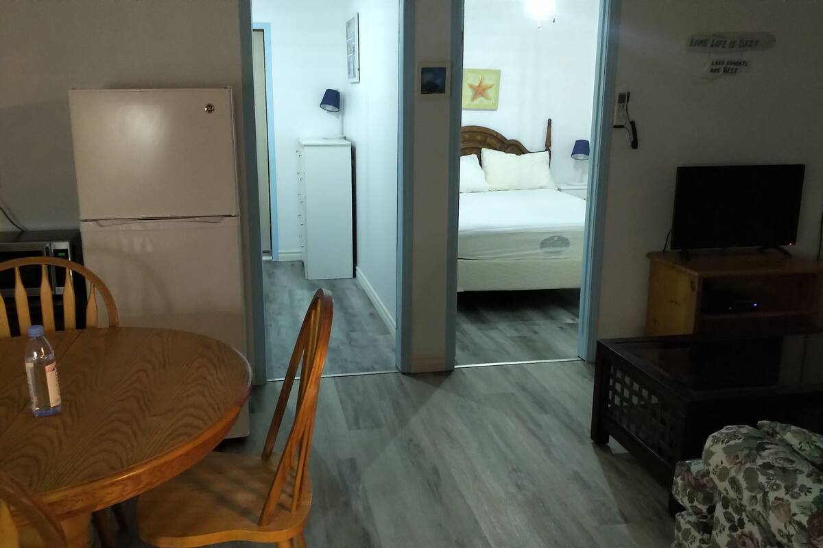 A hotel room with a bed, a TV, a desk, and a dining area with a table and chairs.
