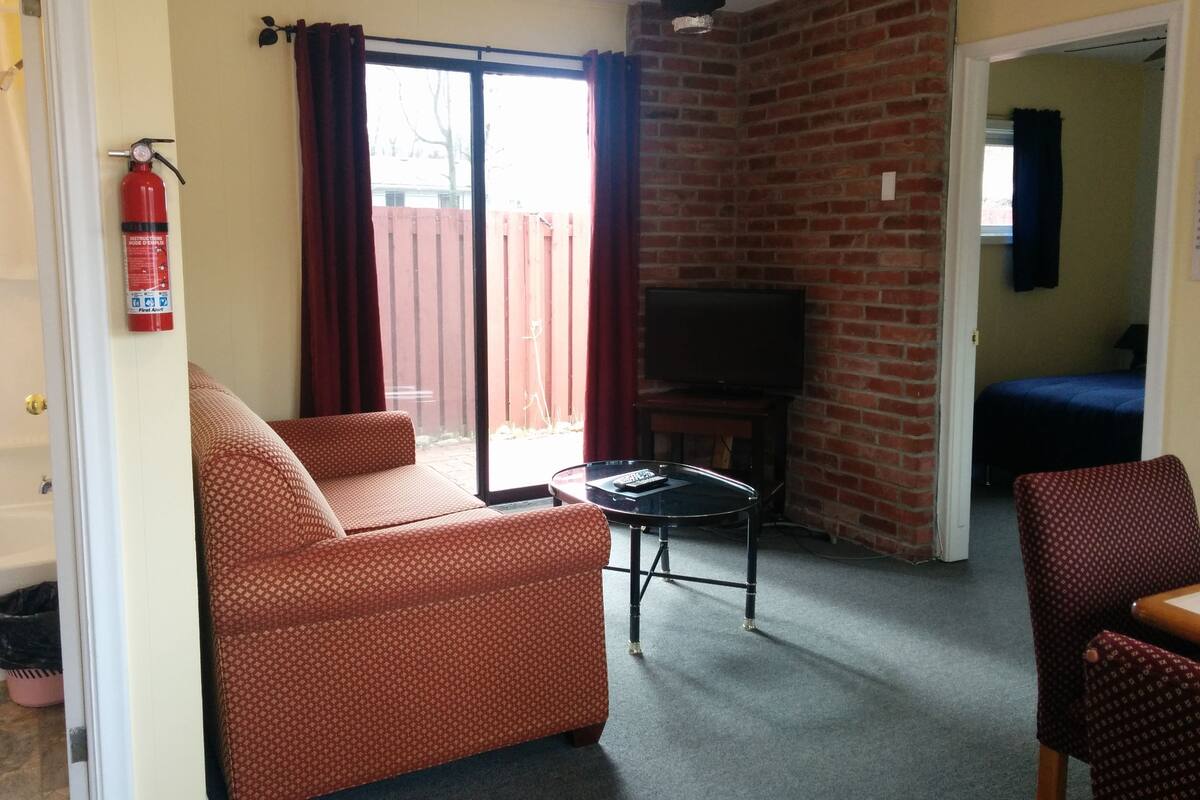 A living room with a sofa, a small table, a TV, and a brick wall.