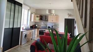 A compact kitchen with wooden cabinets, a washing machine, and a dining area with a red sofa. - Holiday Home in Crux-la-Ville near Lake (Crux-La-Ville)