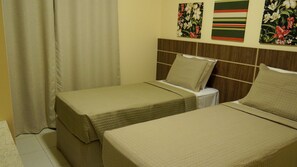 A hotel room with two single beds, a wooden headboard, and floral artwork on the wall. - Residencial Portinari (Porto Seguro)