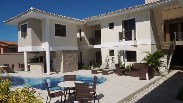 A two-story house with a swimming pool, outdoor seating, and a covered patio area.