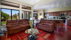 A spacious living room with two brown sofas, a glass coffee table, and a view of the outdoors. - Chandler - 4 Bedroom Home - Chandler (Chandler)
