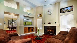 A living room with a fireplace, a television, and a pool table. - Chandler - 4 Bedroom Home - Chandler (Chandler)