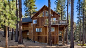 A multi-story wooden cabin surrounded by tall pine trees.