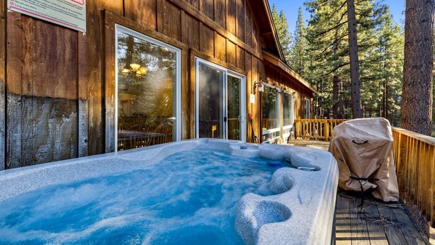 A wooden cabin with a hot tub and a covered grill area.