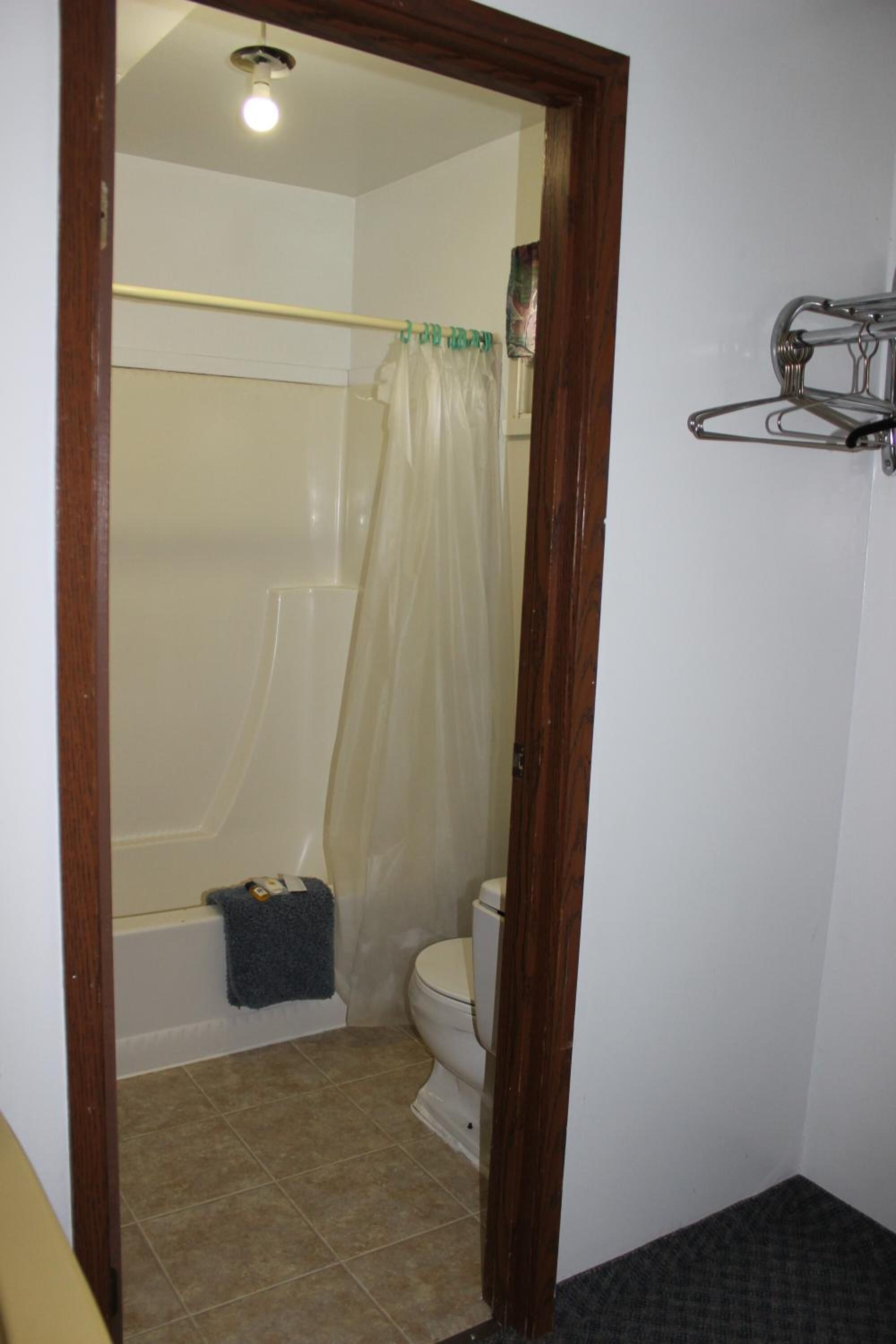 Een badkamer met een douche, toilet en een handdoekrek.