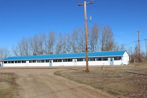 A single-story building with a blue roof and white walls, featuring a row of windows along one side.