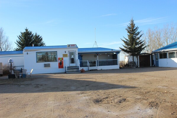 A building with a blue roof, a covered outdoor area, and a dirt ground.