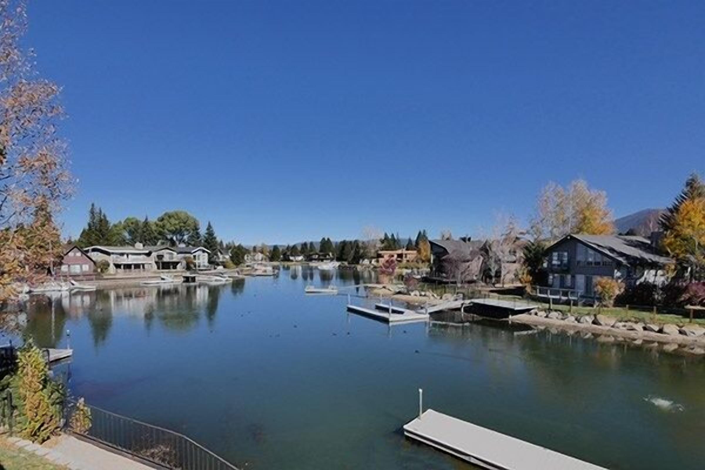 A calm lake with docked boats, surrounded by residential buildings and trees.