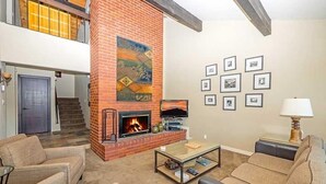 A living room with a fireplace, two sofas, a coffee table, and a TV. - 2130 Monterey Drive 4 Bedroom Home by RedAwning (South Lake Tahoe)