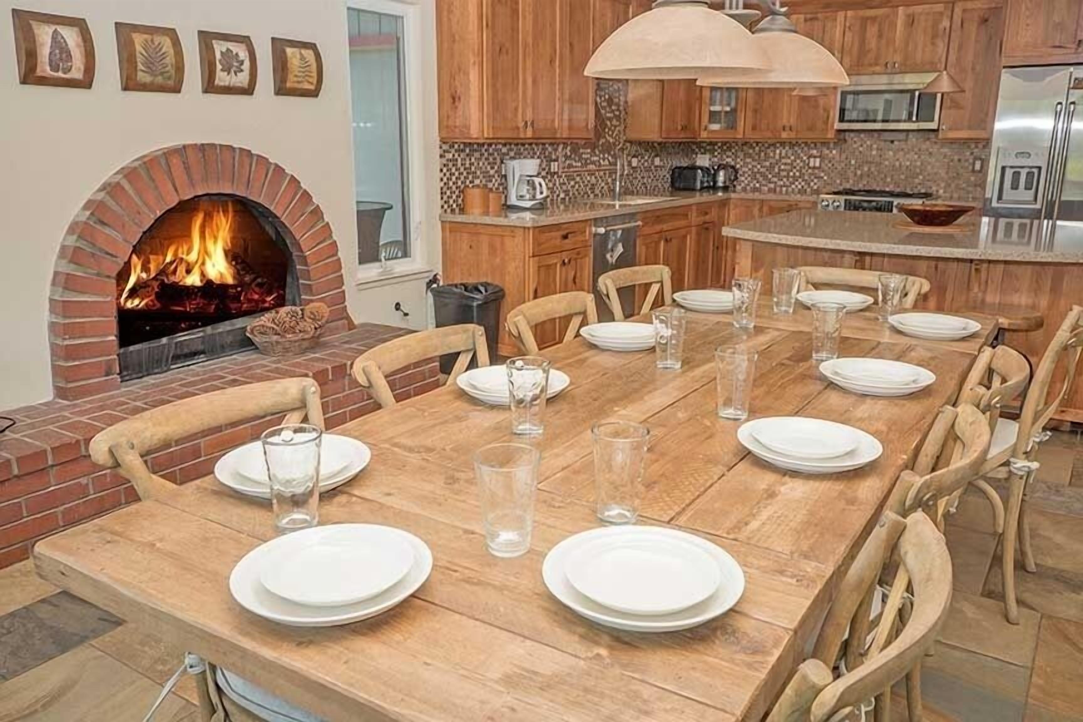 Zona pranzo con camino in mattoni, tavolo in legno e sedie.