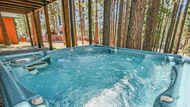 A hot tub in a covered outdoor area surrounded by tall trees. - 2460 Lupine Trail 6 Bedroom Home by RedAwning (South Lake Tahoe)