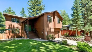 A two-story wooden house with a front porch, a staircase, and a fenced yard.
