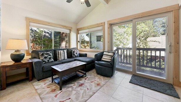 A sunlit room with a sofa, armchair, coffee table, and a lamp.