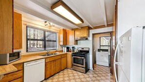 A compact kitchen with wooden cabinets, a built-in oven, a microwave, a sink, and a refrigerator.