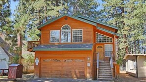 A wooden cabin with a garage, a covered porch, and a staircase leading to the entrance.