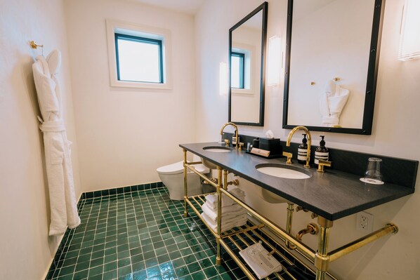 Un baño con dos lavamanos, un espejo grande y una ventana.