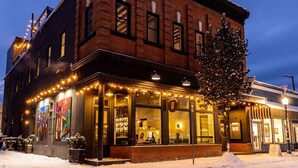 A brick building with a bar and restaurant on the ground floor, featuring large windows and outdoor seating. - Eleven Revelstoke Lodge (Revelstoke)