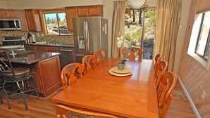 Une cuisine avec des meubles en bois, un réfrigérateur en acier inoxydable, un four à micro-ondes et une table à manger avec des chaises.