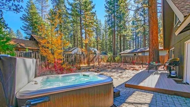 A hot tub in a backyard with wooden decks and a forest backdrop. - 3542 Bobby Grey Circle 3 Bedroom Cabin by RedAwning (South Lake Tahoe)