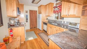 Una cocina compacta con armarios de madera, encimera de granito, refrigerador, lavavajillas y tostadora.