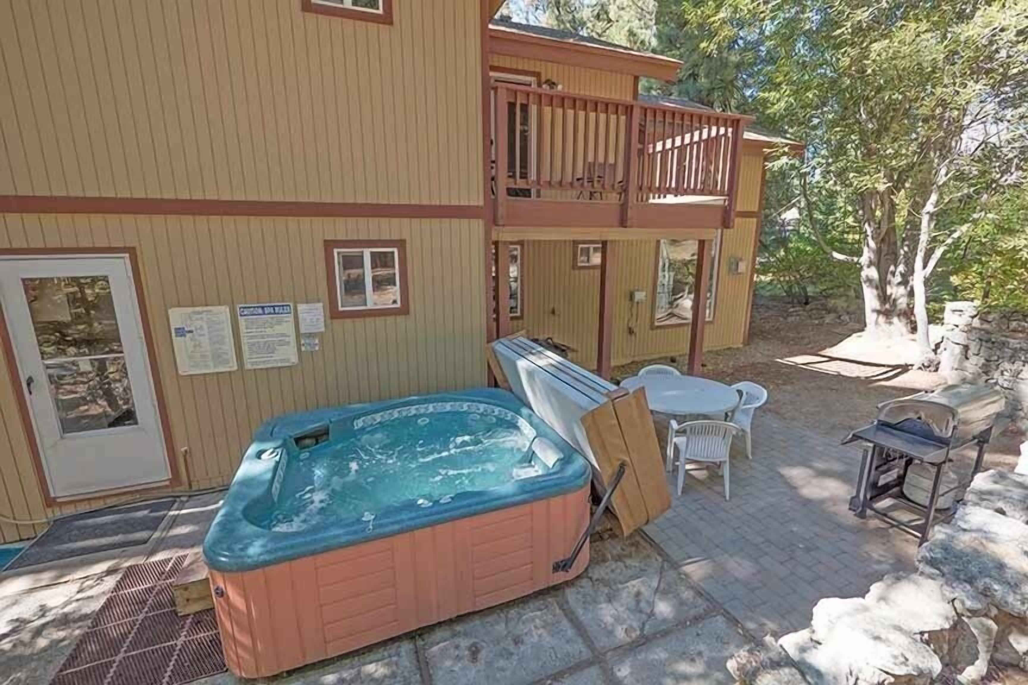 En tvåvåningsbyggnad med ett bubbelbad, utomhusmöbler och en grillplats.