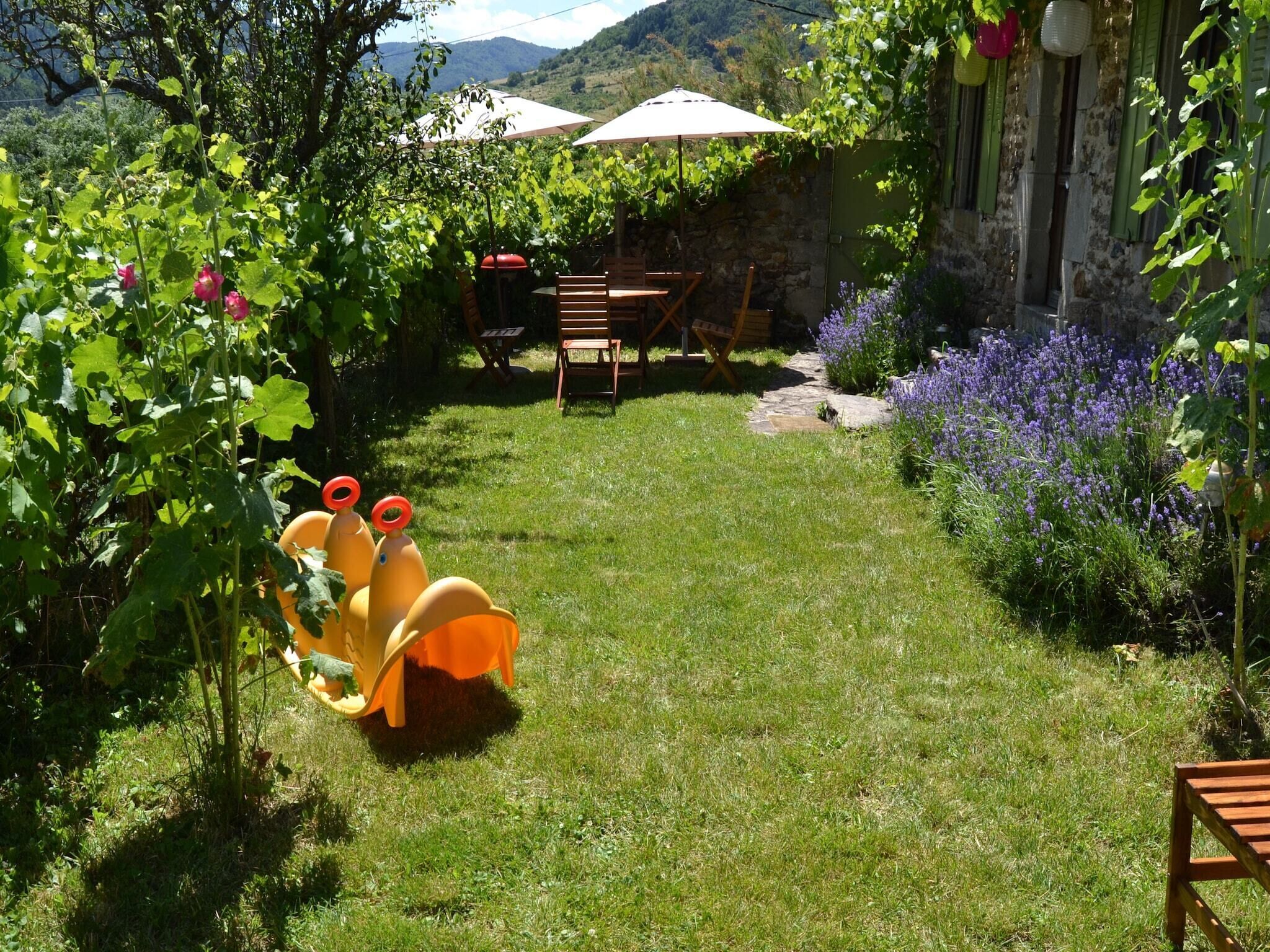 A garden with a wooden table and chairs, surrounded by lush greenery and flowering plants.