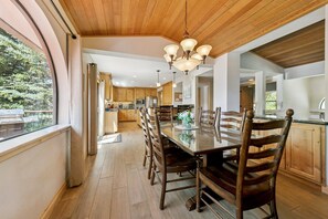 A spacious kitchen with wooden cabinets, a dining table with chairs, and a view of the outdoors. - 596 Danube Drive 3 Bedroom Home by RedAwning (South Lake Tahoe)