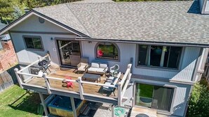 A two-story house with a covered patio, outdoor seating, and a large window.