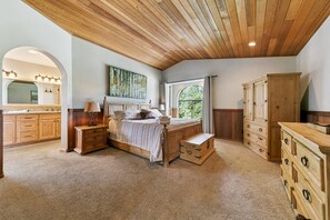 A bedroom with a large bed, wooden headboard, a window with curtains, and a view of greenery outside. - 596 Danube Drive 3 Bedroom Home by RedAwning (South Lake Tahoe)