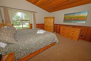 Un dormitorio con una cama grande, cómoda de madera y un cuadro en la pared.
