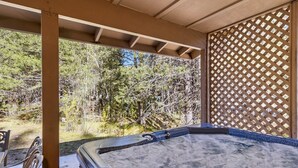 Un bain à remous avec une terrasse en bois et une vue sur une zone boisée.