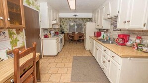 A compact kitchen with white cabinets, a wooden chair, a dining table, and a refrigerator. - 948 Merced Avenue 3 Bedroom Home by RedAwning (South Lake Tahoe)