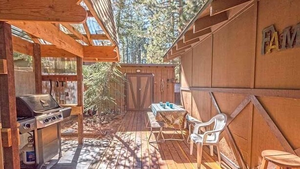 An outdoor patio with a grill, a table with chairs, and a wooden fence. - 948 Merced Avenue 3 Bedroom Home by RedAwning (South Lake Tahoe)