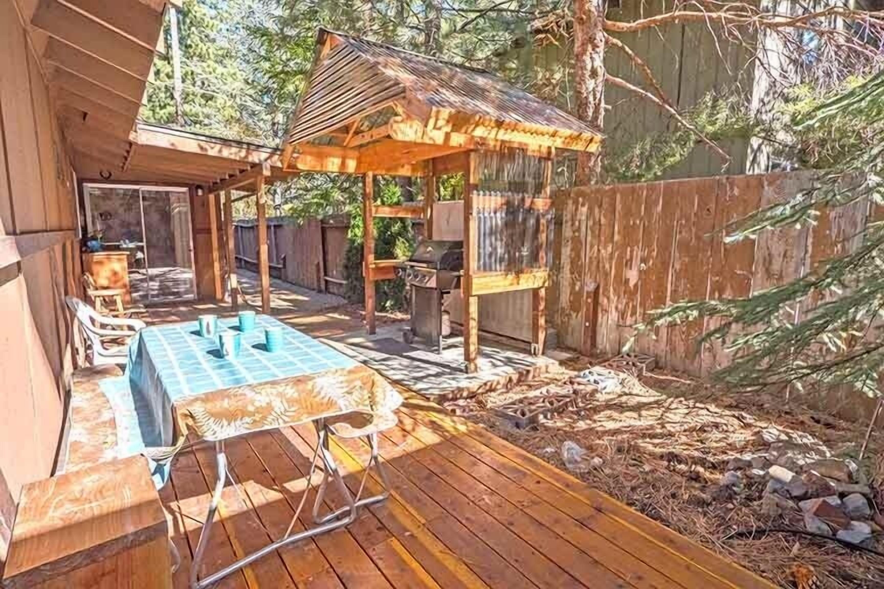 A wooden deck with a barbecue area, a covered seating area, and a pool.