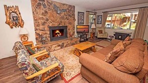 A cozy living room with a stone fireplace, comfortable seating, and a view of the outdoors. - 948 Merced Avenue 3 Bedroom Home by RedAwning (South Lake Tahoe)