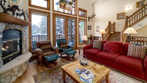 A cozy living room with a fireplace, a red sofa, a wooden coffee table, and a stone fireplace surround. - Crosstimbers 2784 3 Bedroom Townhouse by RedAwning (Steamboat Springs)