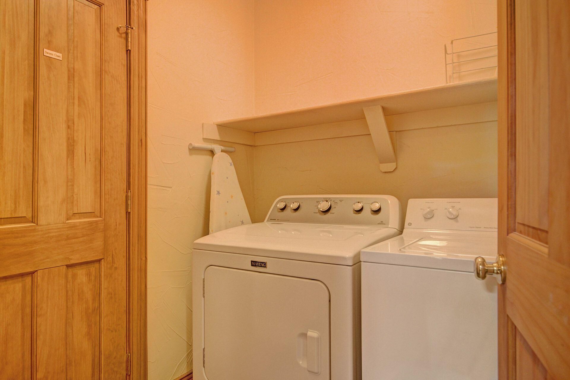 Une buanderie équipée d’un lave-linge et d’un sèche-linge à chargement frontal, de meubles en bois et d’un porte-serviettes.