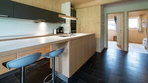 Une cuisine moderne avec un lambris en bois, un îlot central doté de tabourets de bar, un four encastré et une grande fenêtre.