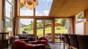 Un intérieur moderne avec une cheminée, un canapé en cuir et une vue sur un paysage verdoyant grâce à de grandes fenêtres.