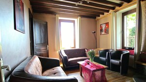 Un salon avec un canapé en cuir marron, une table recouverte d’une nappe rouge et un plancher en bois.