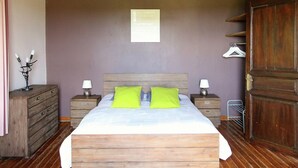 Une chambre à coucher avec un lit en bois, deux tables de chevet avec des lampes, une armoire en bois et un luminaire fixé au mur.