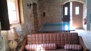 A stone-walled room with a brown leather sofa, a table tennis table, and a lamp. - Historical Charming Vintage Villa with 4 bedrooms & country views 4 Villa by RedAwning (Alcobaça)