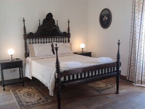 A traditional four-poster bed with a wooden headboard, two bedside tables with lamps, and a floral-patterned curtain. - Historical Charming Vintage Villa with 4 bedrooms & country views 4 Villa by RedAwning (Alcobaça)